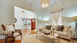 A spacious living room with a sofa, armchair, coffee table, and a dining area in the background. - Walk to Broad St! Family Home in Historic District (Thomasville)