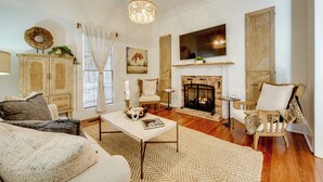 A cozy living room with a fireplace, a sofa, a coffee table, and a chandelier. - Walk to Broad St! Family Home in Historic District (Thomasville)