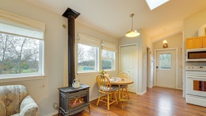 A cozy living room with a fireplace, wooden dining table, and chairs. - Olympic Mtn Views! Cozy Carriage House in Sequim (Sequim)