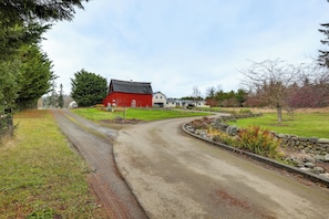A rural road leading to a red barn and white house. - Olympic Mtn Views! Cozy Carriage House in Sequim (Sequim)