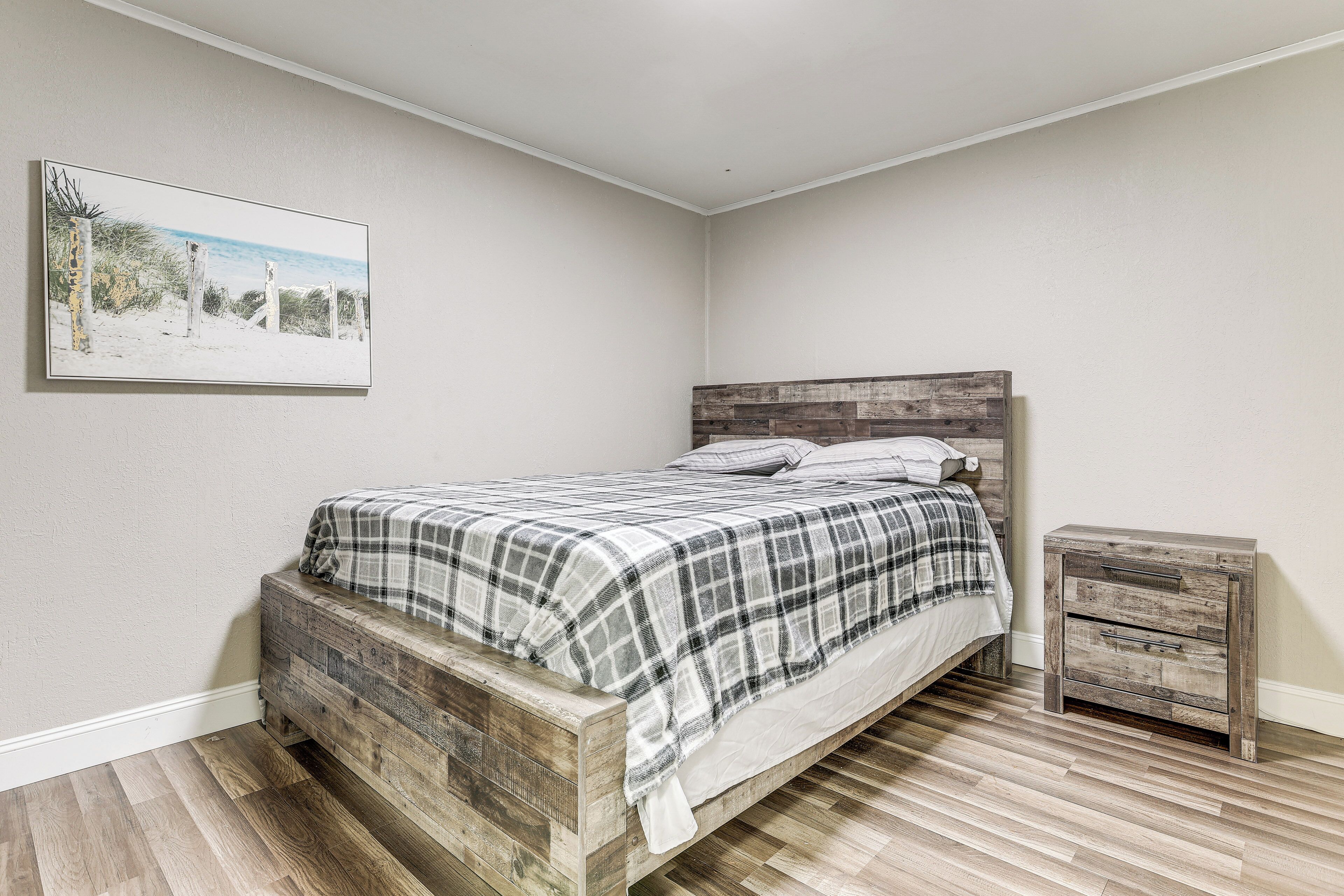 A bedroom with a bed, a nightstand, and a wall-mounted picture.