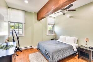 Ein Schlafzimmer mit Bett, Nachttischen, einem Schreibtisch und einem Deckenventilator.