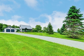 Ein Haus mit Auffahrt, Garage und einem großen Nadelbaum.