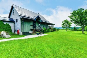 Ein Haus mit geneigtem Dach, einer Veranda und einem gepflegten Rasen.