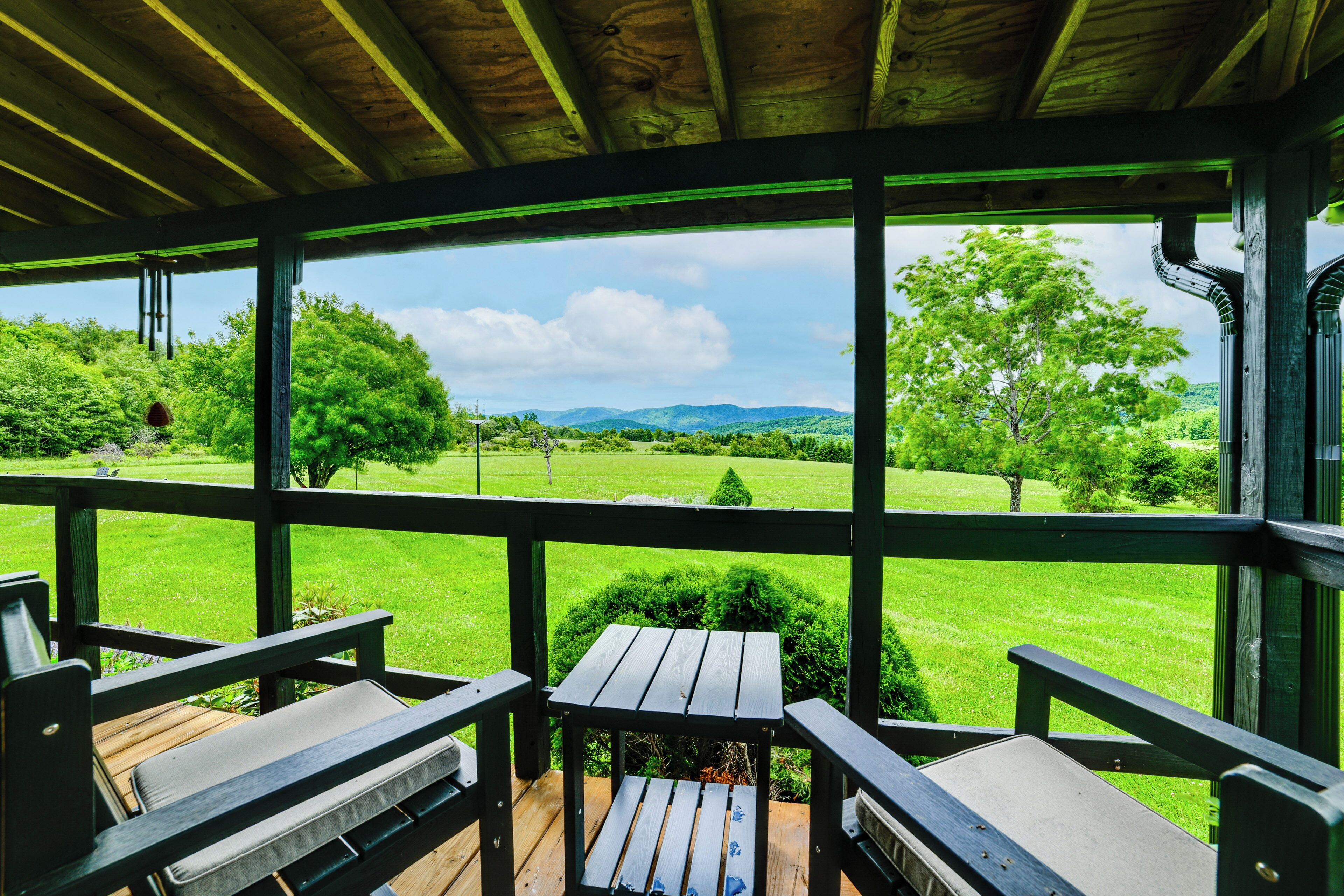 A covered outdoor seating area with a view of a green landscape.