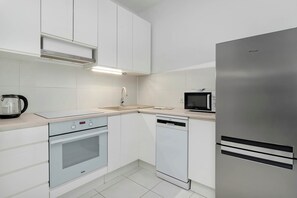 A modern kitchen with white cabinetry, a stainless steel refrigerator, a dishwasher, an oven, and a microwave. - Comfortable Apartment | Parking, Gym and Balcony (Gdańsk)