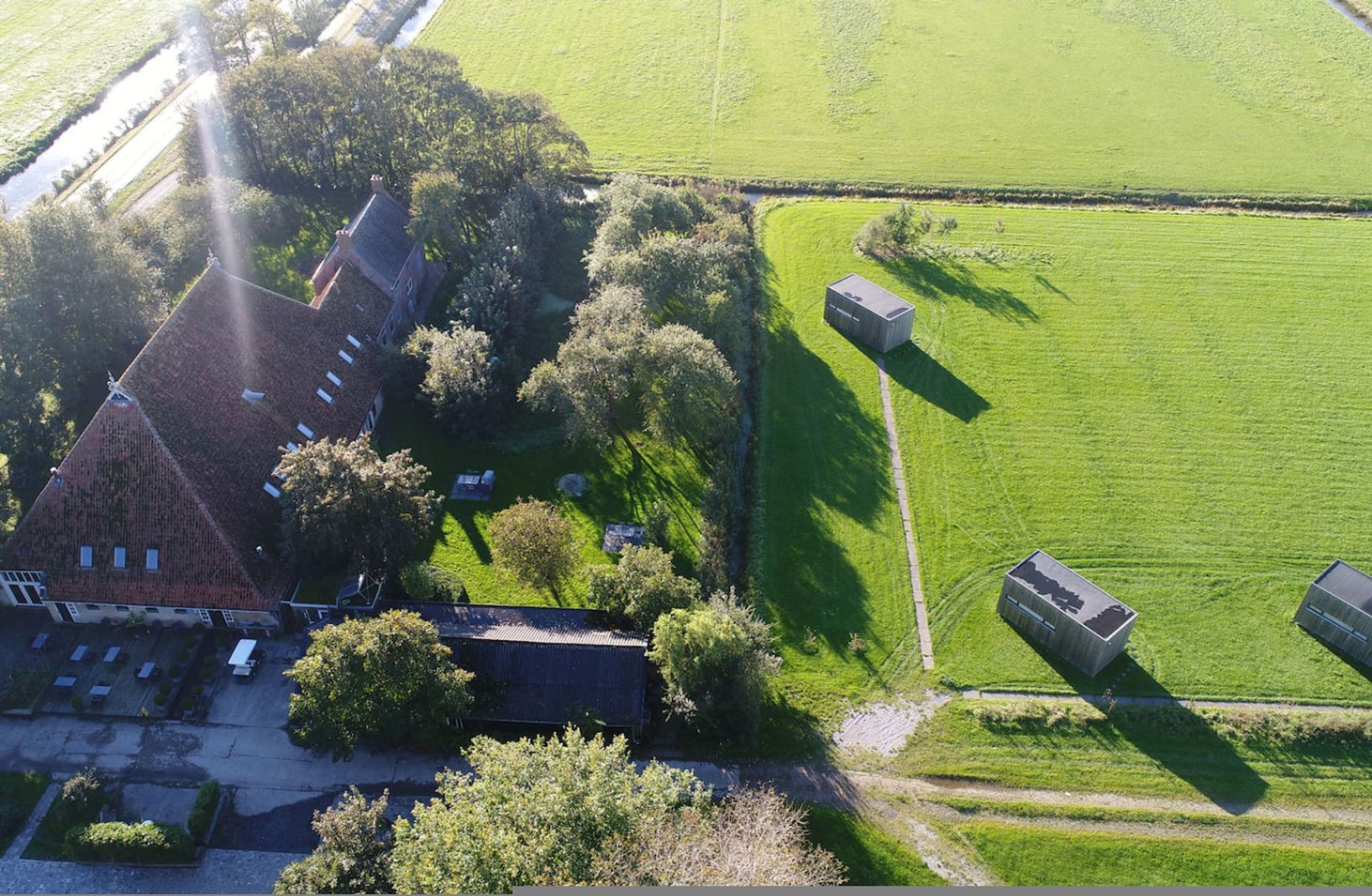 Vista aérea de una propiedad rural con una casa grande, varios graneros y extensos campos verdes.