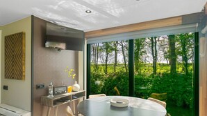 A modern kitchen with a built-in stove, a large window, and a dining area with a round table and chairs. - Fokke Sleat Houseboat (Weidum)