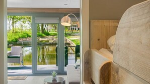 A modern interior with a wooden bunk bed, a small round table, and a view of a pond outside. - Doeke Sleat Houseboat (Weidum)