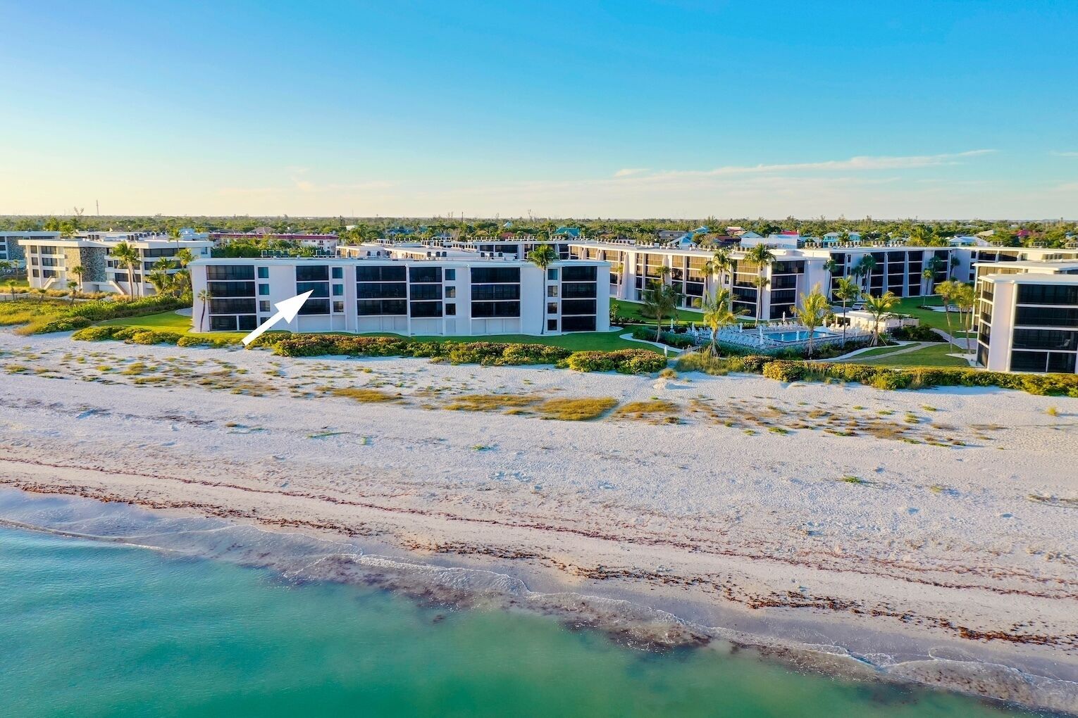 Un hotel frente a la playa con arquitectura moderna, una playa de arena y una vista despejada del océano.