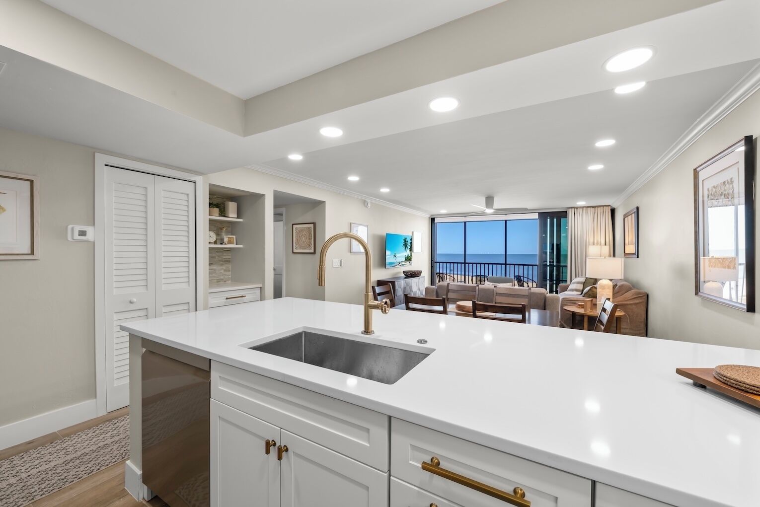 A modern kitchen with white cabinetry, a large island with a sink, and recessed ceiling lights.
