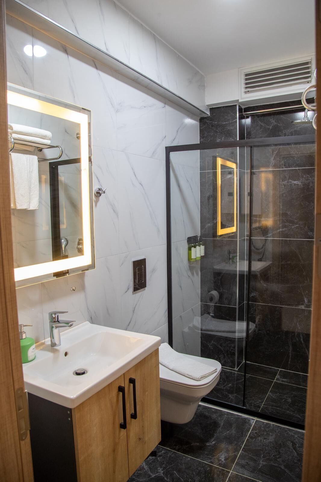 Un baño moderno con tocador de mármol, inodoro y cabina de ducha de vidrio.