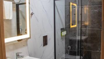 Un baño moderno con tocador de mármol, inodoro y cabina de ducha de vidrio.
