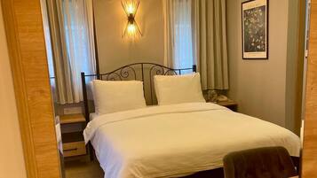 Une chambre d’hôtel avec un lit, une table de chevet, un miroir et un lustre.