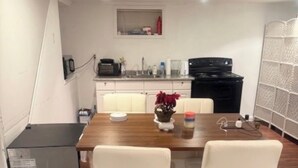 A compact kitchen with a dining area, featuring a central island with two bar stools, a refrigerator, and a stove.