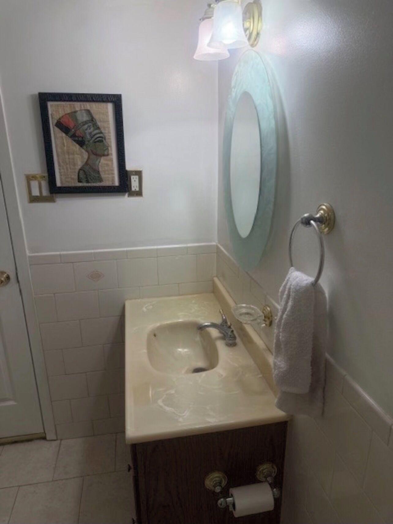 Un baño pequeño con un lavabo, un espejo, un perchero para toallas y un cuadro en la pared.