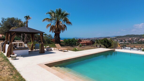 Uma área de piscina com um gazebo, espreguiçadeiras e vista para a paisagem.