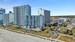 A high-rise hotel with multiple balconies, a swimming pool, and a beach view. - Salt Air Style- 2 BR Balcony Retreat (Myrtle Beach)