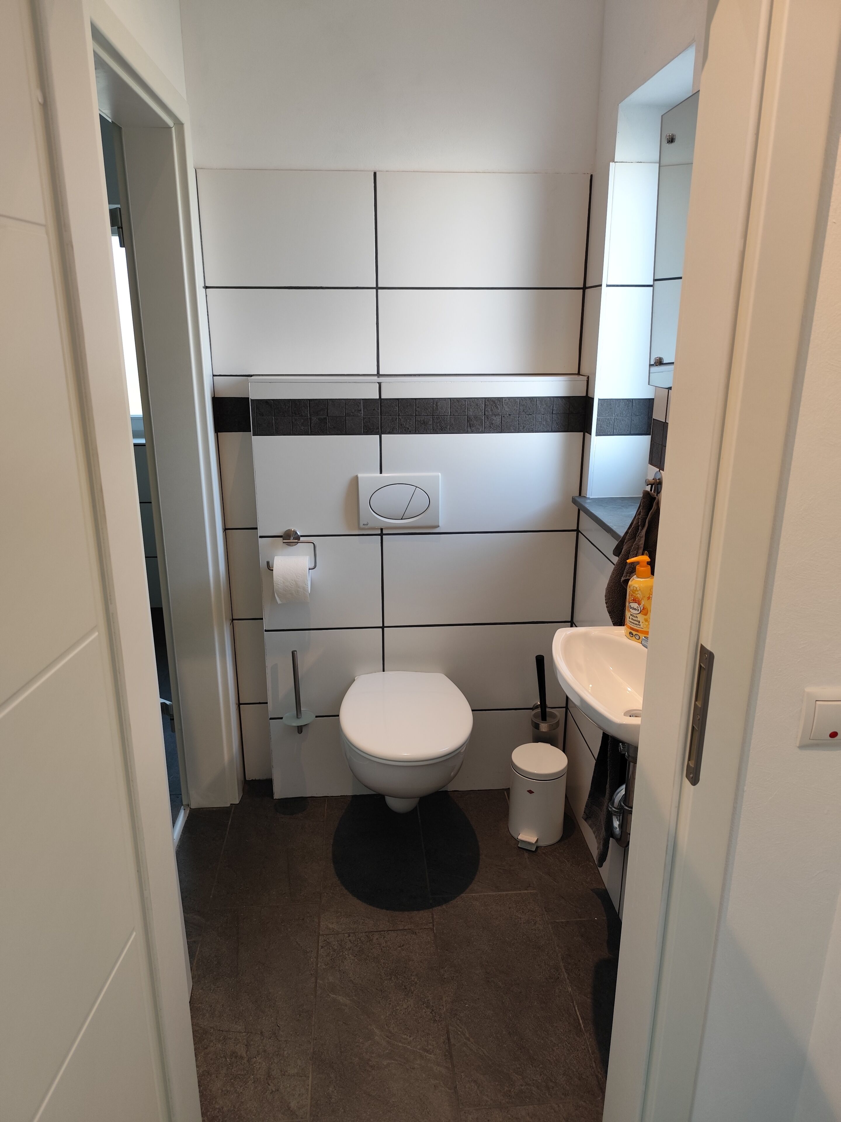 A bathroom with a toilet, bidet, sink, and a mirror.