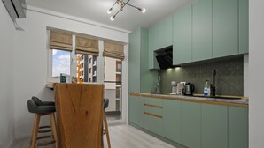 Eine moderne Küche mit grünen Schränken, einem Holztisch und Blick ins Freie.