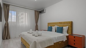 Ein ordentlich eingerichtetes Schlafzimmer mit einem Bett, Nachttischen und einer Klimaanlage.