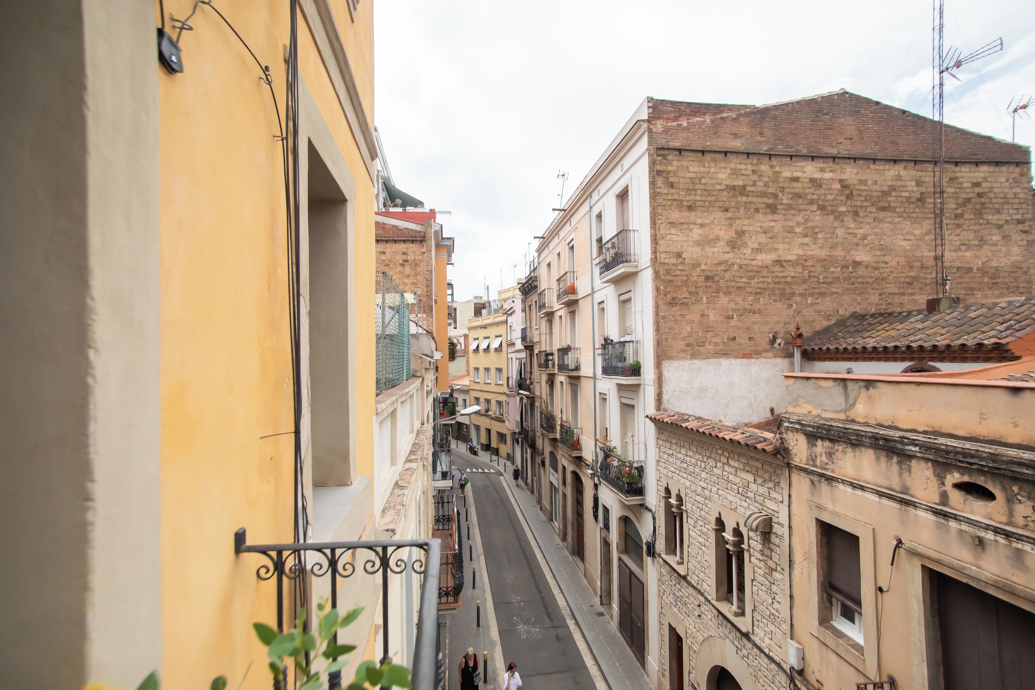 A narrow street flanked by buildings with balconies and a clear sky.