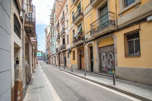 A narrow street lined with multi-story buildings, featuring balconies with plants and decorative railings. - BBarcelona Sants Flat (Barcelona)