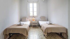 A room with two beds, a small table with a lamp, and a window with shutters. - BBarcelona Sants Flat (Barcelona)