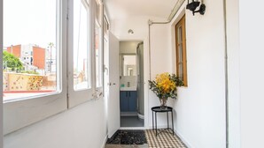 A narrow hallway with a checkered floor, a window on the left, and a door leading to a bathroom. - BBarcelona Sants Flat (Barcelona)