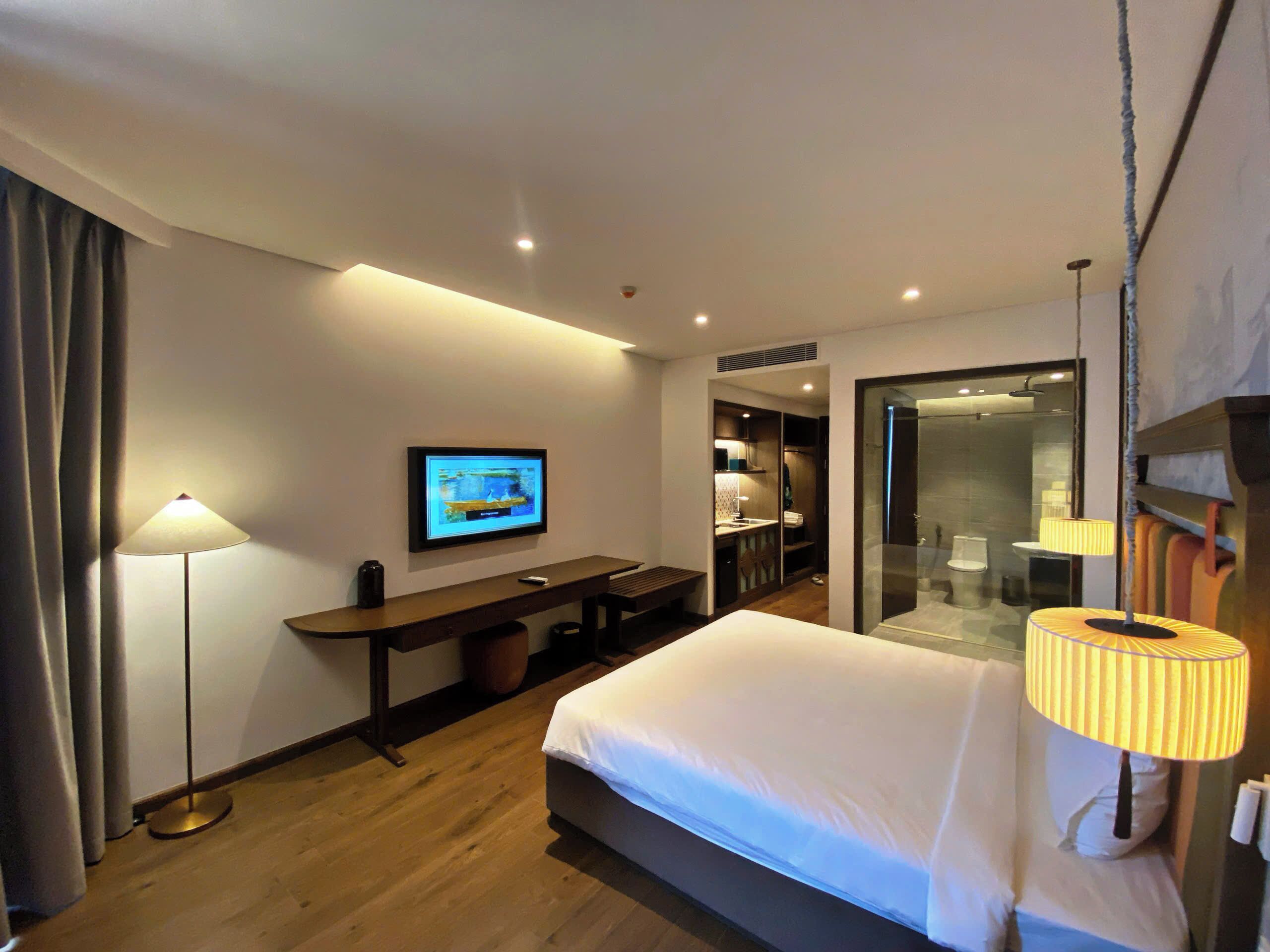 Ein Hotelzimmer mit Bett, Schreibtisch, Fernseher, Badezimmer und Dusche.