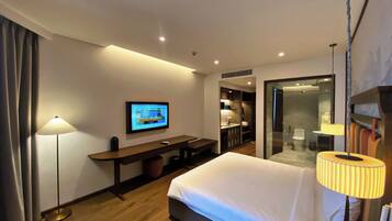 Ein Hotelzimmer mit Bett, Schreibtisch, Fernseher, Badezimmer und Dusche.