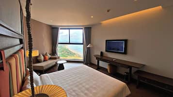 Habitación de hotel con una cama grande, un escritorio, un televisor y vistas a la playa.