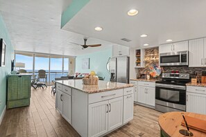 A kitchen with white cabinets, a large island, stainless steel appliances, and a view to the outside. - 1008 Waters Edge Resort 1 Bedroom Condo (Murrells Inlet)