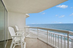 Ein Balkon mit weißen Stühlen und Blick auf den Ozean.