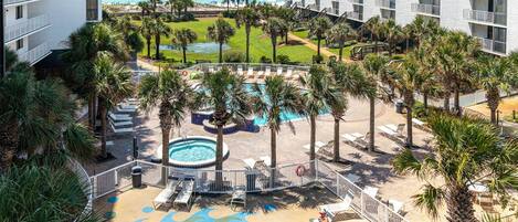 A resort with multiple swimming pools, palm trees, and a view of the ocean.