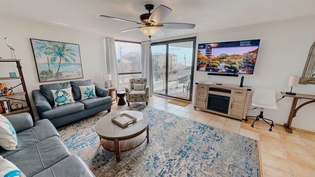 A modern living room with a sofa, coffee table, and a TV on a stand. - Mainsail 321 2 Bedroom Condo (Miramar Beach)