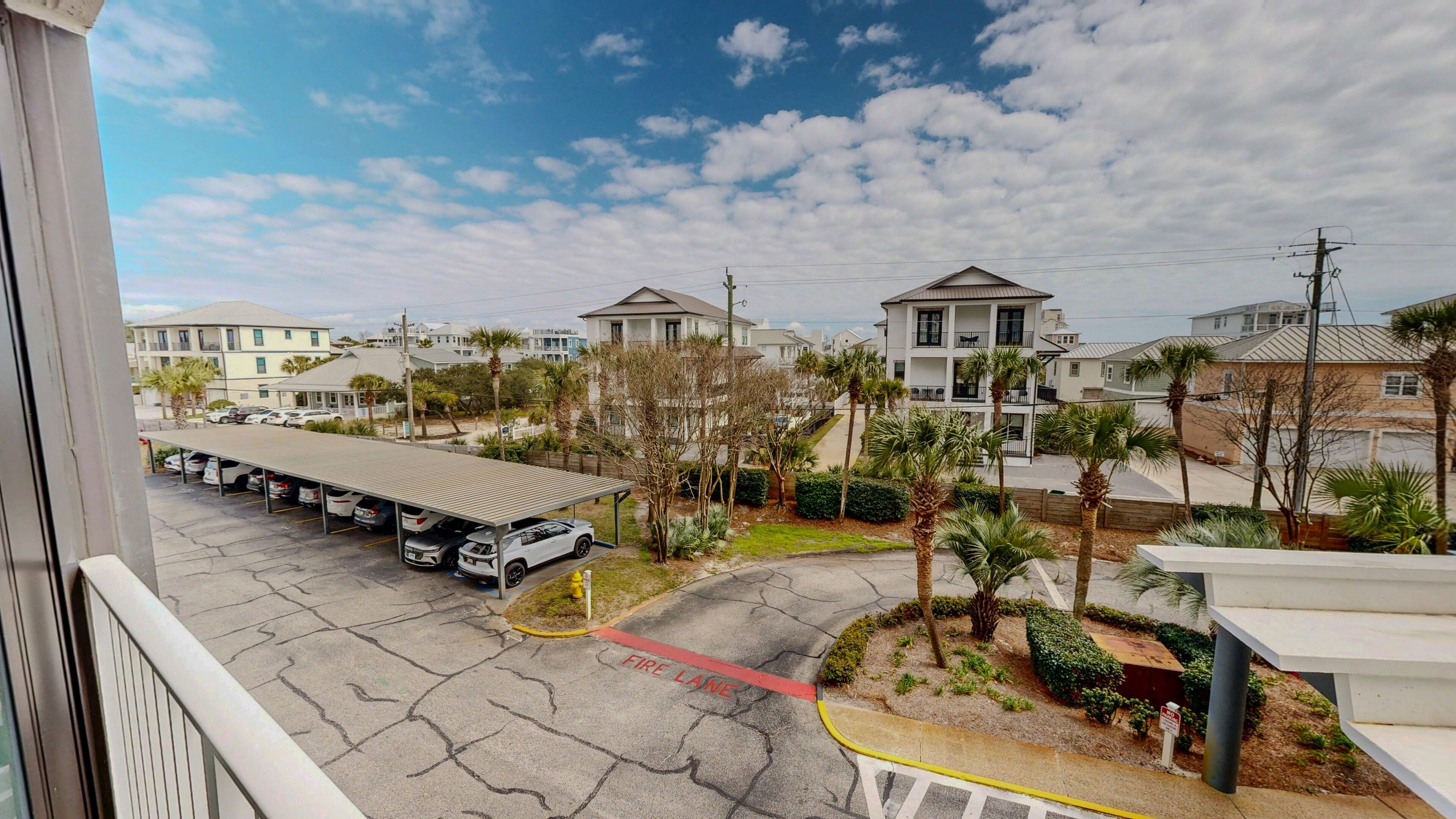 A residential area with a fire lane, parked cars, and houses with balconies.