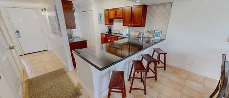A modern kitchen with a central island, wooden cabinets, and a tiled backsplash.
