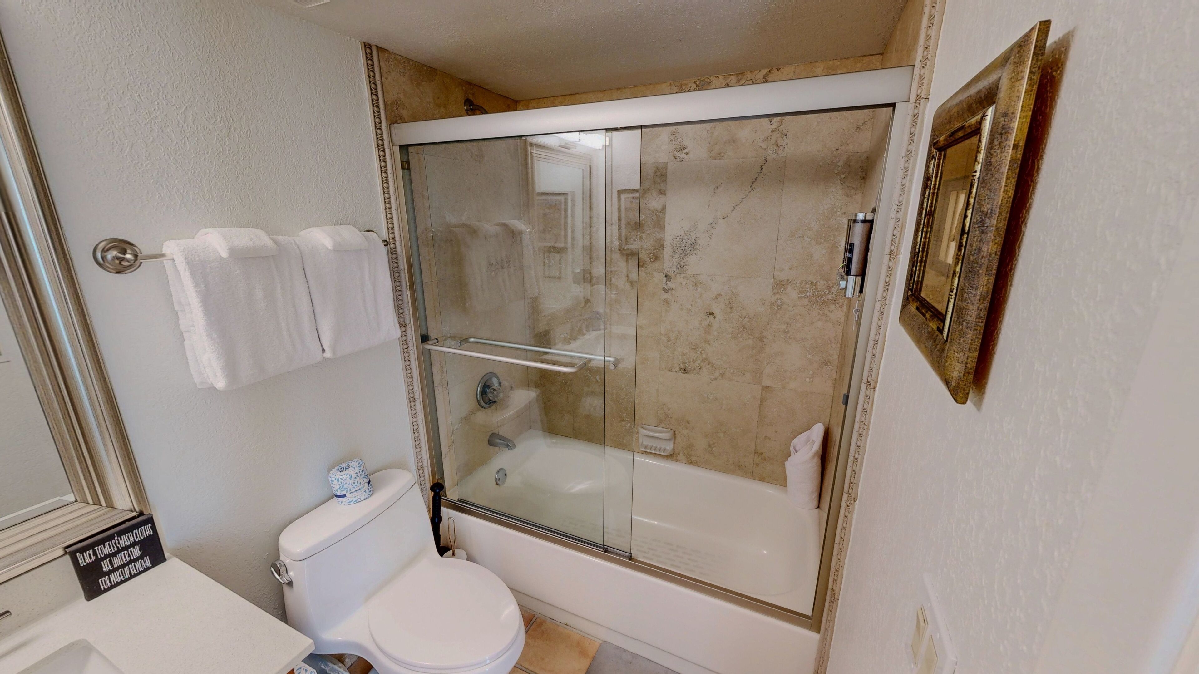 A bathroom with a glass-enclosed shower, a toilet, and a sink.