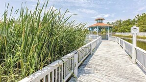 Une promenade en bois mène à un belvédère où un panneau indique les activités de pêche.