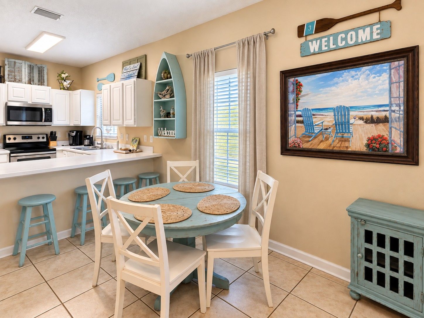 A kitchen with white cabinets, a microwave, and a stove. There is a dining area with a round table and four chairs.