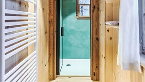 A narrow wooden hallway leading to a room with a teal wall and a small window.