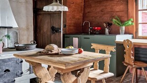 A rustic kitchen with a wooden table, chairs, and a sink.