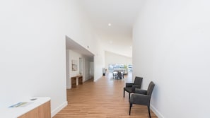 A spacious hallway with wooden flooring, a dining area with chairs, and a view of the outside. - 2 Ulmarra - Spacious 4-bedroom waterfront holiday home (Harrington)