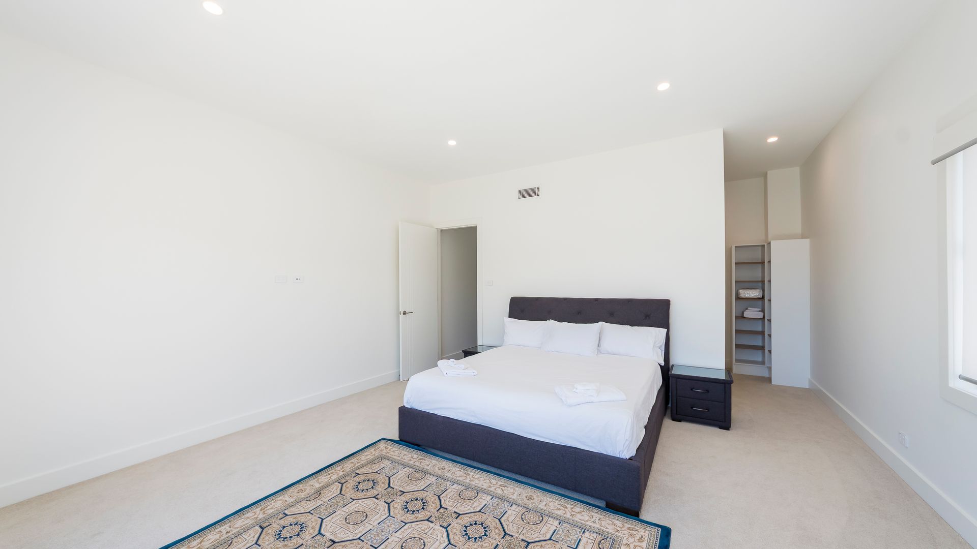 A bedroom with a bed, bedside table, and a walk-in closet.