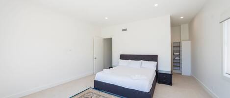 A bedroom with a bed, bedside table, and a walk-in closet.