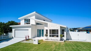 A modern two-story house with a garage, large windows, and a stone accent wall. - 2 Ulmarra - Spacious 4-bedroom waterfront holiday home (Harrington)