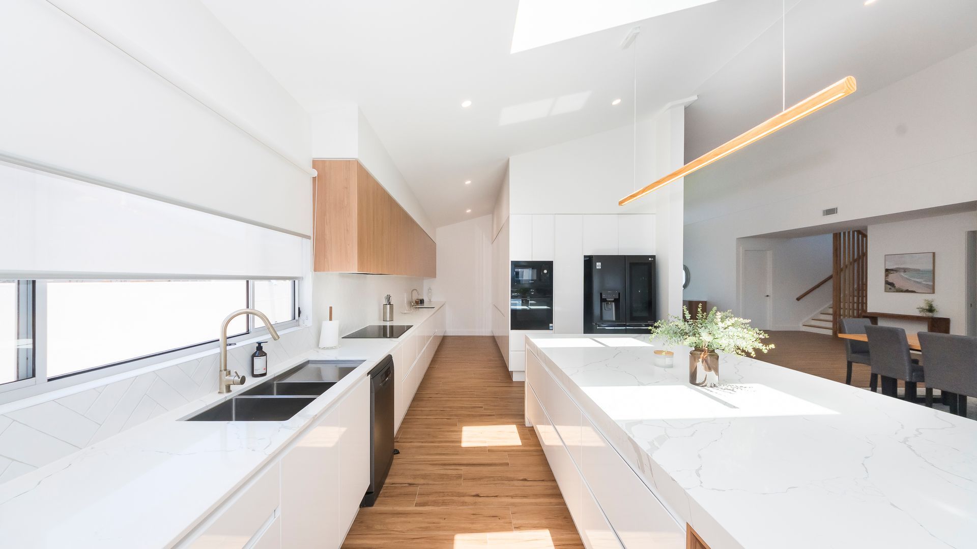 A modern kitchen with white cabinetry, a wooden floor, and a central island.