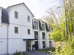 Un immeuble moderne à plusieurs étages, doté d’un toit plat, de grandes fenêtres et d’un espace d’entrée abrité.