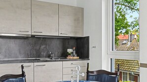 Een moderne keuken met een ronde tafel, een decoratieve anker-presentatie en uitzicht op het buitenleven door een raam.